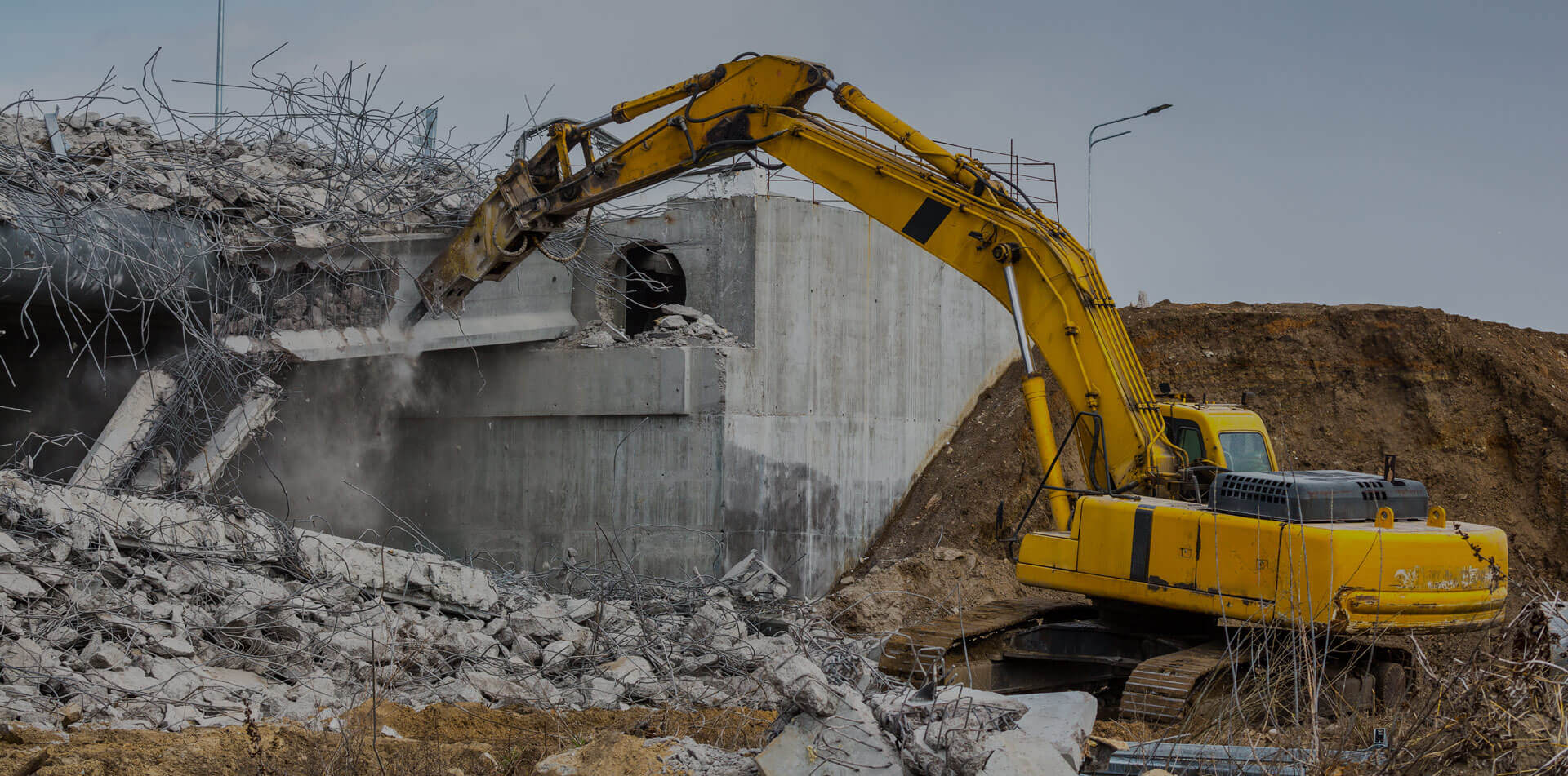 Professional demolition of reinforced concrete structures using industrial hydraulic hammer.